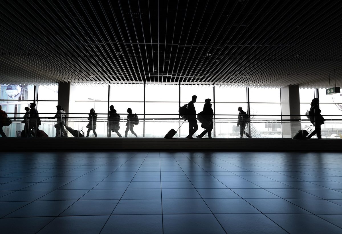 Passengers walking through an airport terminal with cabin bags and suitcases in the UAE